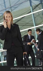 Businesswoman using mobile phone with coworkers in background