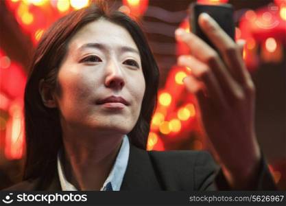 Businesswoman using smart phone, night street, red lanterns on the background