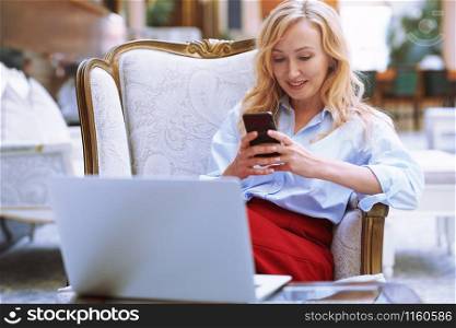 Businesswoman using smartphone in the modern bank lobby