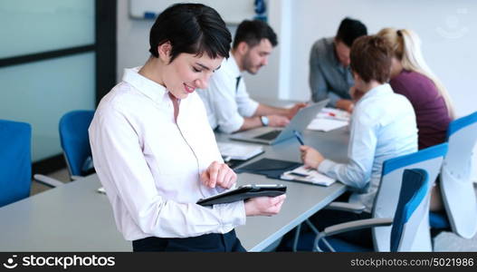 Businesswoman using tablet with coworkers in backgorund having meeting