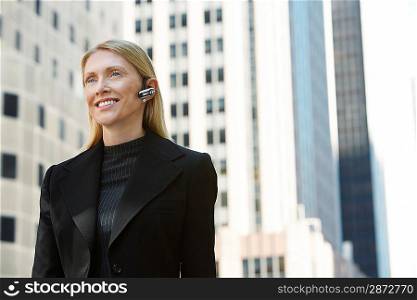 Businesswoman using wireless headset outdoors