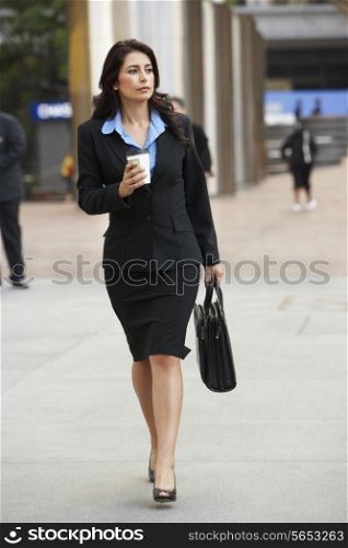 Businesswoman Walking Along Street Holding Takeaway Coffee