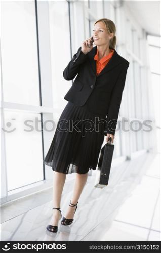 Businesswoman walking in corridor talking on cellular phone