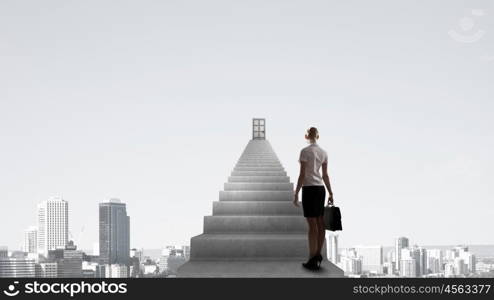 Businesswoman walking up staircase to door in sky. Way to success