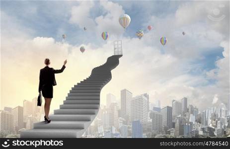 Businesswoman walking up staircase to door in sky. Way to success