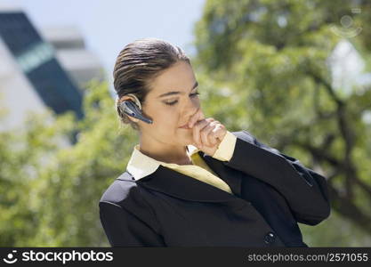 Businesswoman wearing a bluetooth device with her hands covering her mouth