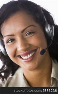Businesswoman wearing headset in office smiling (high key/selective focus)