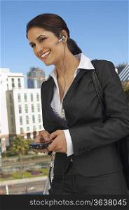 Businesswoman wearing headset, text messaging, outdoors