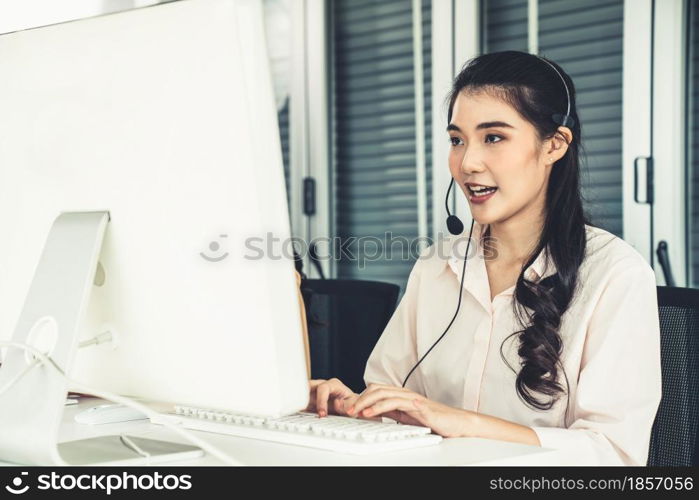 Businesswoman wearing headset working actively in office . Call center, telemarketing, customer support agent provide service on telephone video conference call.. Businesswoman wearing headset working actively in office