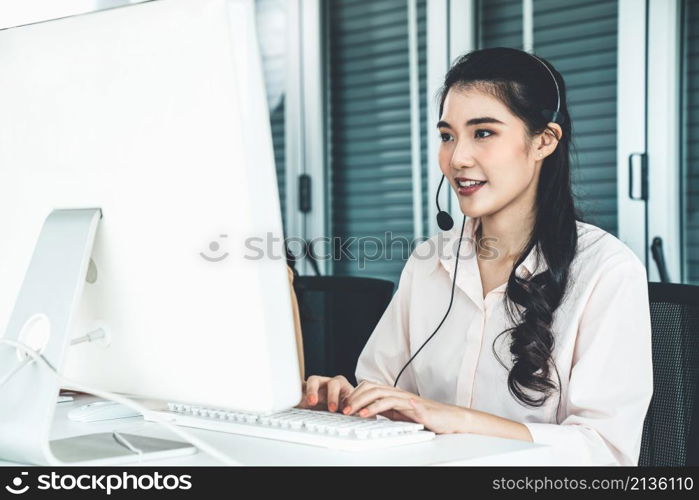 Businesswoman wearing headset working actively in office . Call center, telemarketing, customer support agent provide service on telephone video conference call.. Businesswoman wearing headset working actively in office