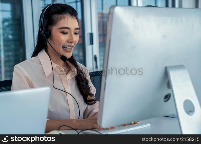 Businesswoman wearing headset working actively in office . Call center, telemarketing, customer support agent provide service on telephone video conference call.. Businesswoman wearing headset working actively in office