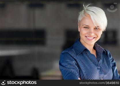 Businesswoman wearing shirt and smiling in front of a dark background