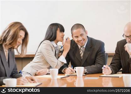 Businesswoman whispering into a businessman&acute;s ear in a meeting