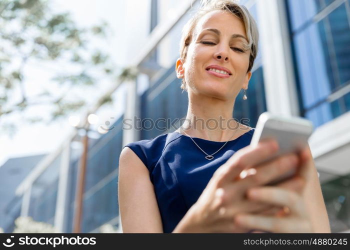 Businesswoman with a phone in a city. Hello there from business lady