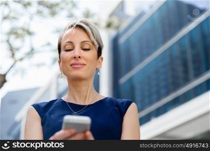 Businesswoman with a phone in a city. Hello there from business lady