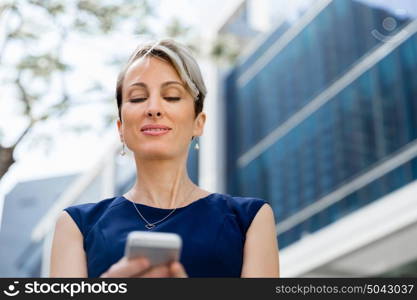 Businesswoman with a phone in a city. Hello there from business lady