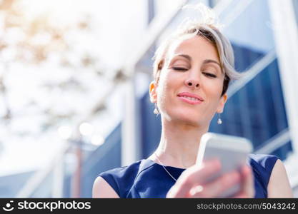 Businesswoman with a phone in a city. Hello there from business lady