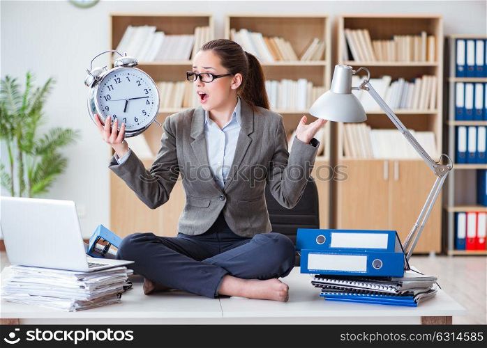 Businesswoman with alarm clock in office