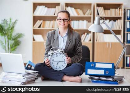 Businesswoman with alarm clock in office