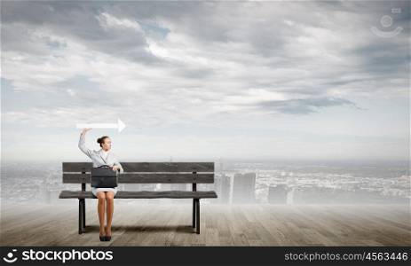 Businesswoman with arrow. Young businesswoman with suitcase sitting on bench