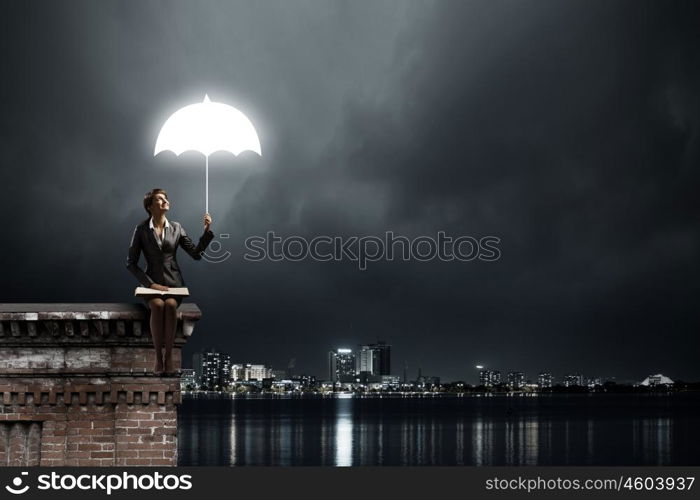 Businesswoman with book. Young businesswoman sitting on top of building with book