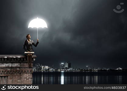 Businesswoman with book. Young businesswoman sitting on top of building with book