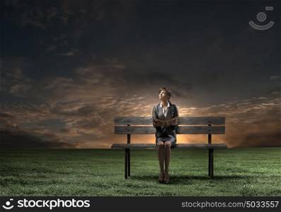 Businesswoman with book. Young smiling businesswoman sitting on bench with book in hands