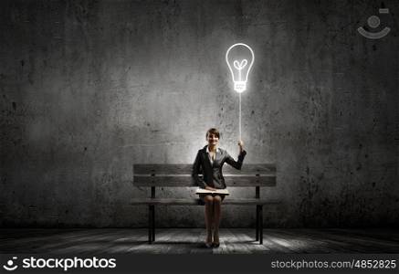 Businesswoman with book. Young smiling businesswoman sitting on bench with book on knees