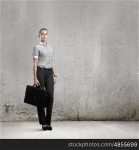 Businesswoman with briefcase. Young attractive businesswoman with suitcase in hand in empty room