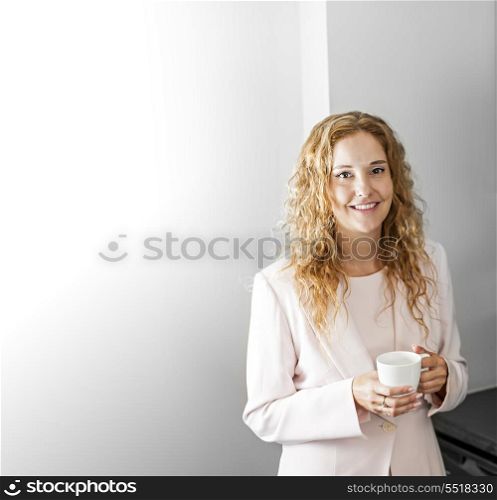 Businesswoman with coffee. Business woman in suit standing and holding coffee cup on break with copy space