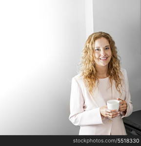 Businesswoman with coffee. Business woman in suit standing and holding coffee cup on break with copy space