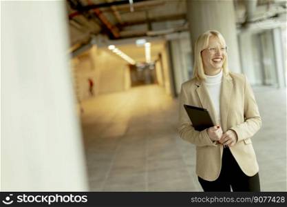 Businesswoman with digital tablet on the modern office hallway