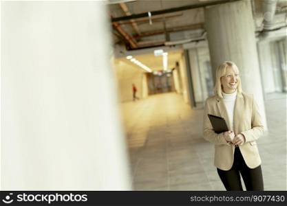 Businesswoman with digital tablet on the modern office hallway