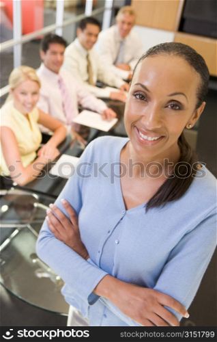 Businesswoman with four businesspeople at boardroom table in background