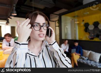 businesswoman with glasses using mobile phone at modern startup open plan office interior