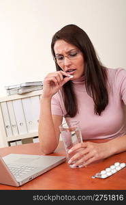 Businesswoman with headache take pill at office