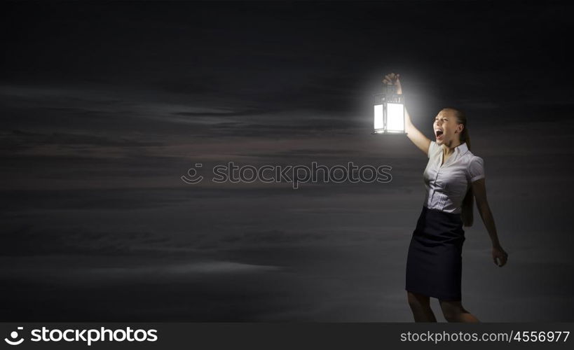 Businesswoman with lantern. Young businesswoman walking in darkness with lantern in hand