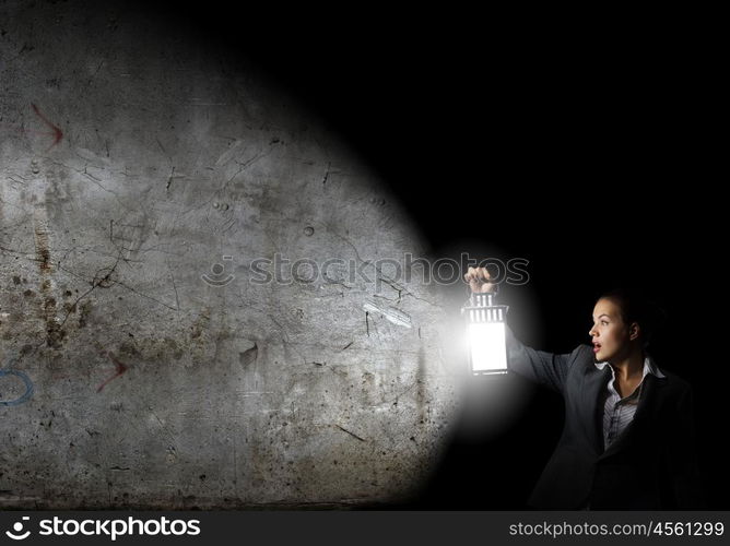 Businesswoman with lantern. Young businesswoman walking in darkness with lantern in hand