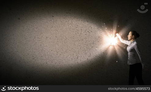 Businesswoman with lantern. Young businesswoman walking in darkness with lantern in hand