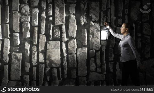 Businesswoman with lantern. Young businesswoman walking in darkness with lantern in hand