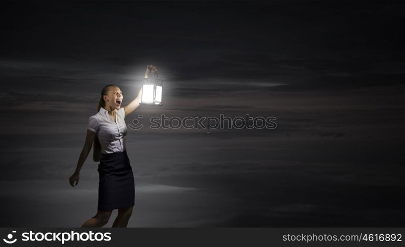 Businesswoman with lantern. Young businesswoman walking in darkness with lantern in hand