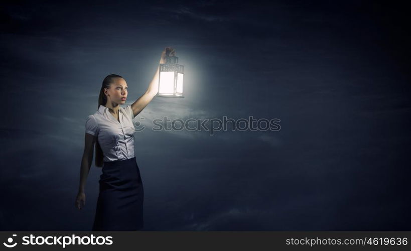 Businesswoman with lantern. Young businesswoman walking in darkness with lantern in hand