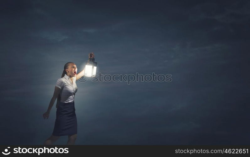 Businesswoman with lantern. Young businesswoman walking in darkness with lantern in hand