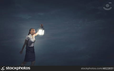 Businesswoman with lantern. Young businesswoman walking in darkness with lantern in hand