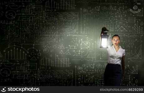 Businesswoman with lantern. Young businesswoman walking in darkness with lantern in hand