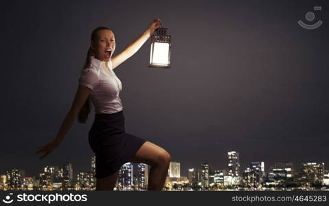 Businesswoman with lantern. Young businesswoman walking in darkness with lantern in hand