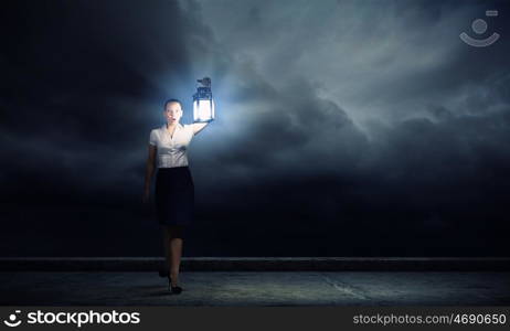 Businesswoman with lantern. Young businesswoman walking in darkness with lantern in hand