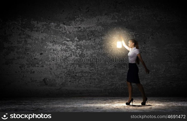 Businesswoman with lantern. Young businesswoman walking in darkness with lantern in hand