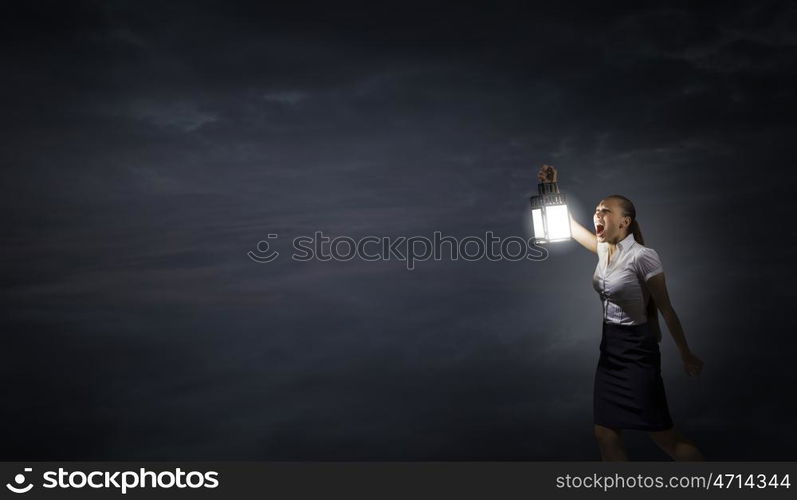 Businesswoman with lantern. Young businesswoman walking in darkness with lantern in hand