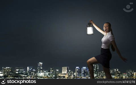 Businesswoman with lantern. Young businesswoman walking in darkness with lantern in hand